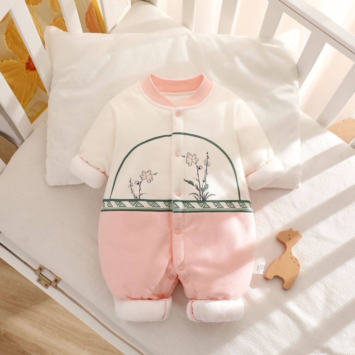 Baby romper with floral embroidery on a crib