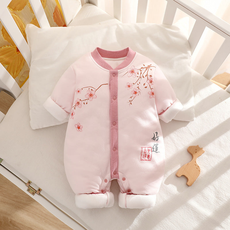 Pink baby romper with floral designs on a crib